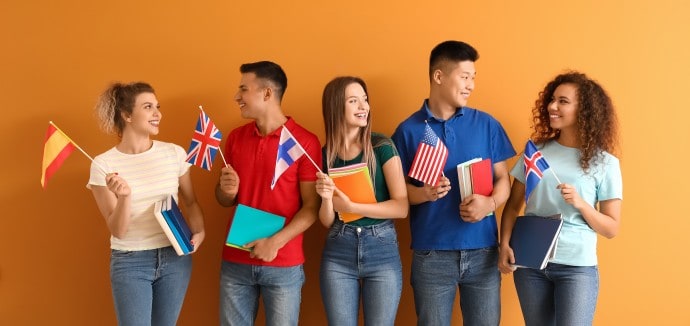 Young students of language school on orange background